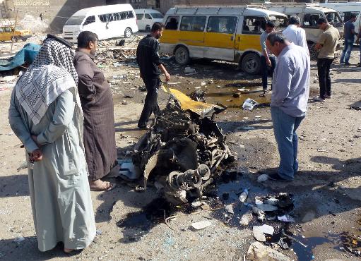 Iraquianos observam os restos de um veículo no local de um atentado em uma estação de ônibus de Bagdá, em 27 de outubro de 2013