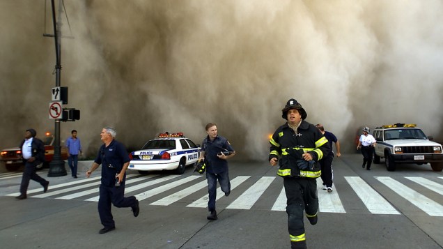 Bombeiros e policiais fogem da nuvem de poeira provocada pela queda de uma das torres do World Trade Center, 11 de setembro de 2001 em Nova York