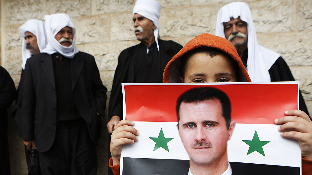Menino da comunidade drusa segura bandeira da Síria com a imagem do presidente Bashar al-Assad, durante uma reunião que marca o Dia da Independência da Síria, em Israel