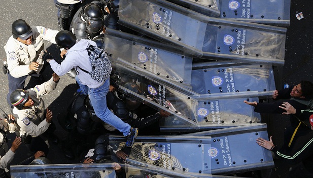 Manifestante pula por cima de cordão de policiais em Caracas durante protesto contra o governo Maduro