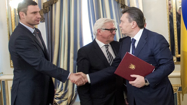 Vitali Klitschko cumprimenta Viktor Yanukovich após assinar o acordo. Atrás deles está o Ministro das Relações Exteriores da Alemanha, Frank-Walter Steinmeier