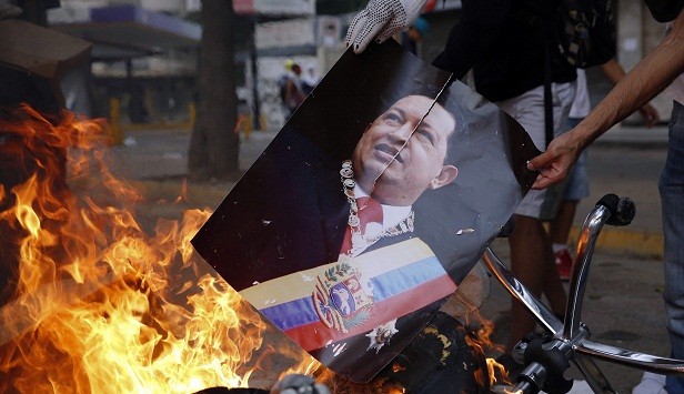 Manifestante queima foto do ex-presidente Hugo Chávez em Caracas