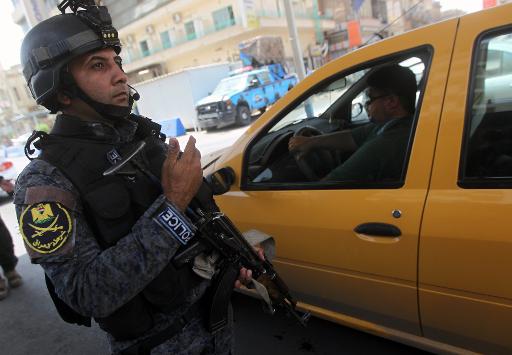 (Julho) Policial inspeciona veículos em um posto de controle de Bagdá