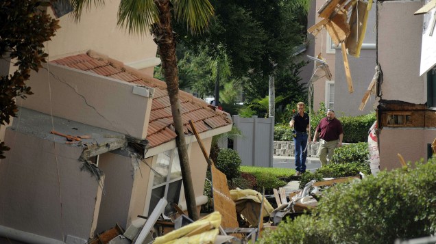 Homens observam buraco que provocou a queda de construções em região perto dos parques da Disney