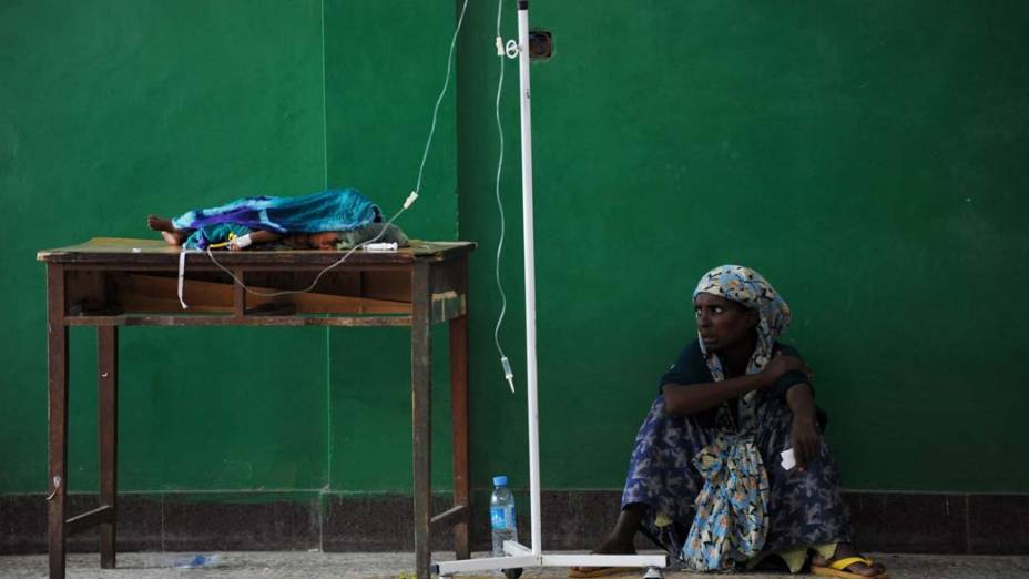Mulher somali aguarda enquanto seu filho é alimentado por via intravenosa em hospital em Mogadíscio, Somália