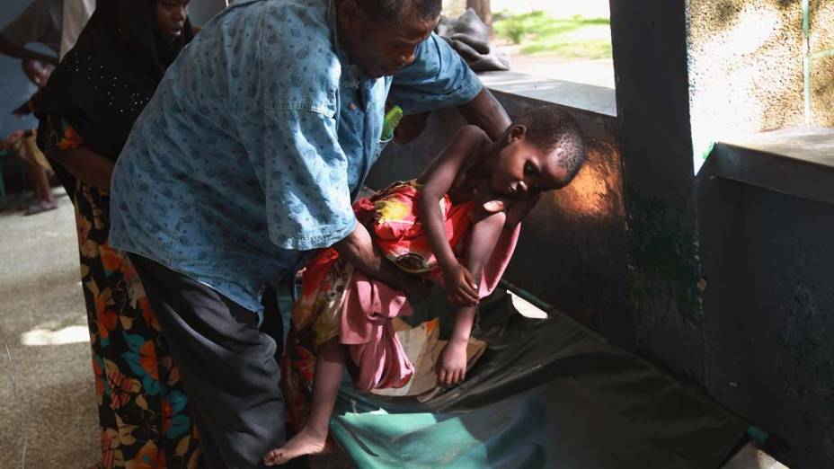 Pai acomoda seu filho doente no hospital Banadir, em Mogadíscio, Somália