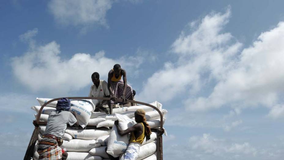 Trabalhadores descarregam caminhão com comida do Programa Alimentar Mundial em Mogadíscio, Somália
