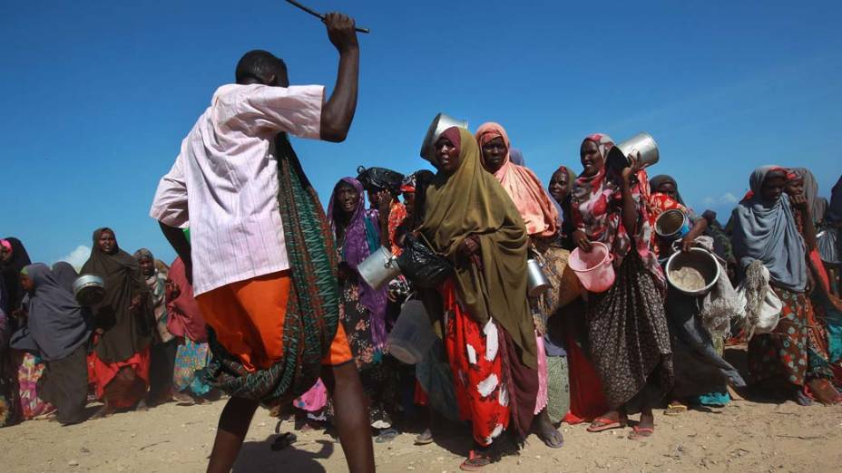 Segurança tenta organizar fila de mulheres somalis que aguardam para receber ajuda alimentar em Mogadíscio, Somália