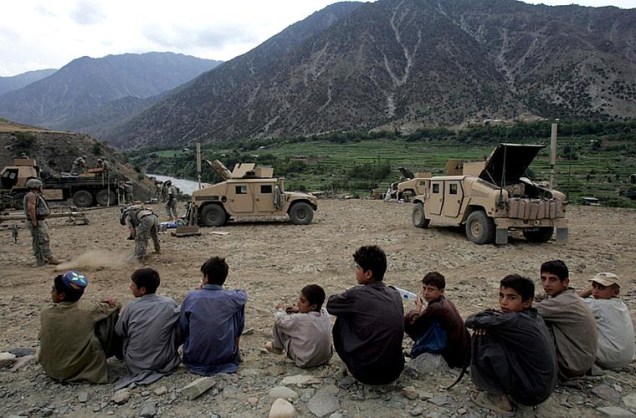 Crianças observam soldados americanos armarem uma nova base perto da fronteira do Paquistão, em 2006.
