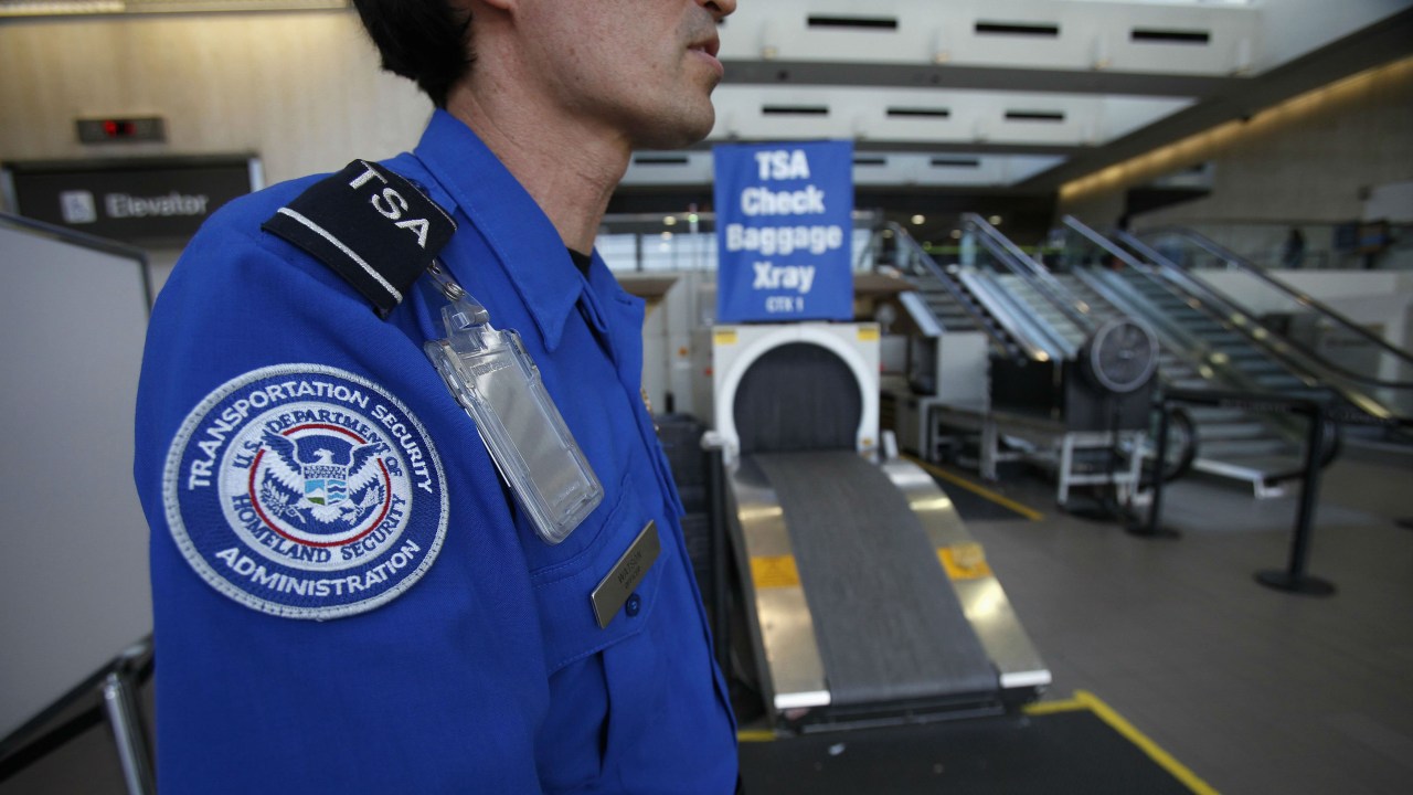 Agente da TSA espera para passar bagagens no raio-x, no aeroporto internacional de Los Angeles