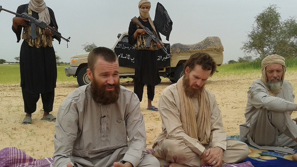 Os três homens, apresentados pela Al-Jazeera como Stephen Malcolm, britânico e sul-africano, Johan Gustafson, sueco, e Sjaak Rijke, holandês, aparecem sentados em tapetes no deserto, rodeados de homens armados