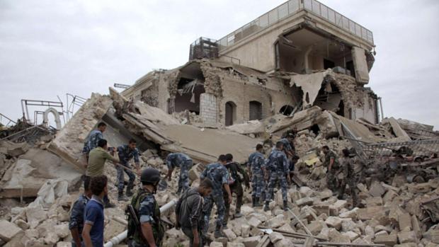 Militares inspecionam os destroços de um hotel que era usado pelas forças do regime sírio em Alepo. O prédio foi destruído por rebeldes em 2014
