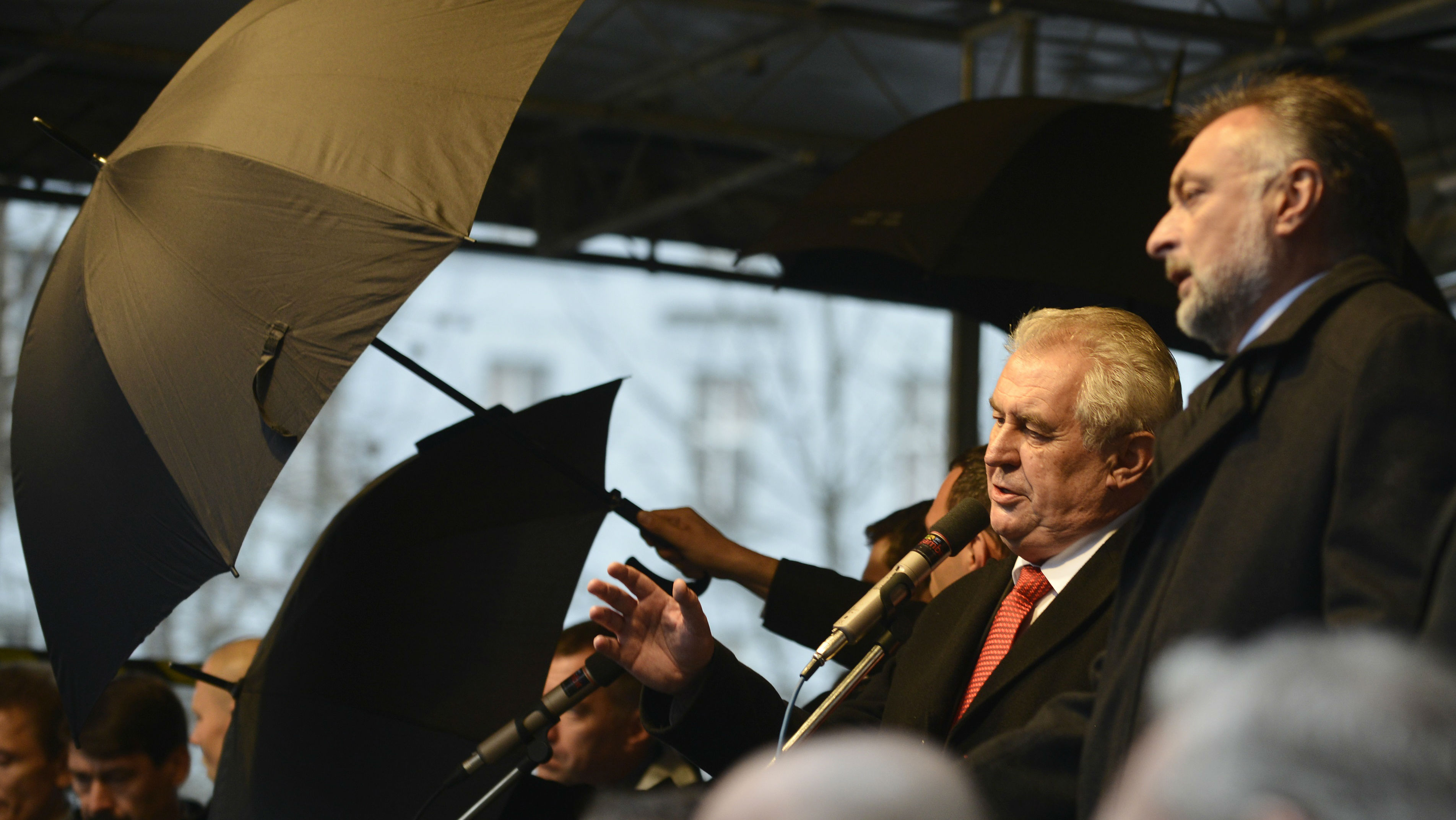 Seguranças tentam proteger o presidente da República Tcheca, Milos Zeman, de ovos atirados por manifestantes