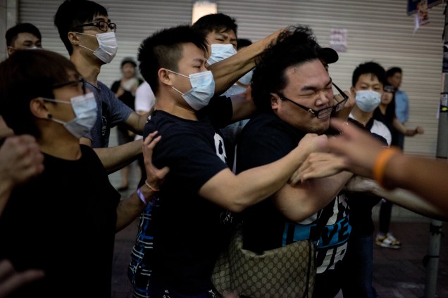Jovens com máscara batem em homem que tentava impedi-los de remover barricadas de uma área ocupada por manifestantes pró-democracia em Hong Kong. Grupos contrários aos protestos entraram em confronto com os manifestantes