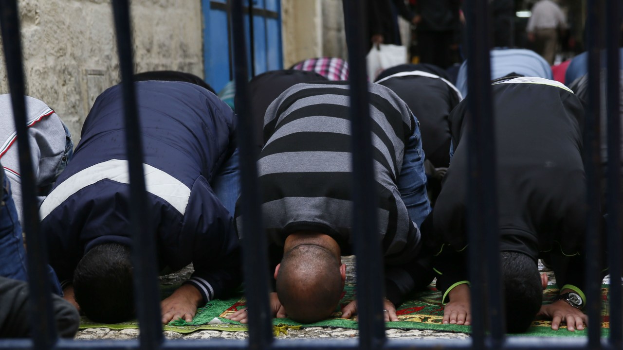 Muçulmanos rezam atrás de barricada policial no Nobre Santuário, na Jerusalém Oriental