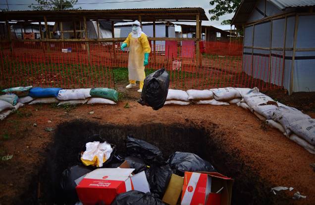 Profissional do Médicos Sem Fronteiras em volta de itens que tiveram contato com infectados pelo ebola momentos antes de serem incinerados em Serra Leoa