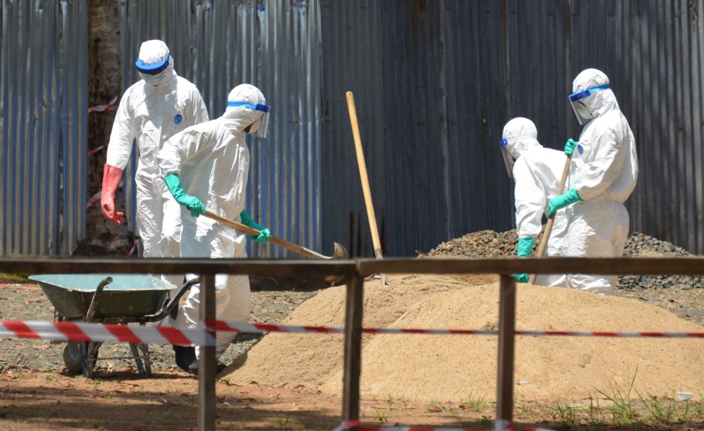 Profissionais de saúde da Libéria em tanque de areia que é utilizado para absorver os fluidos do corpo de vítimas do ebola