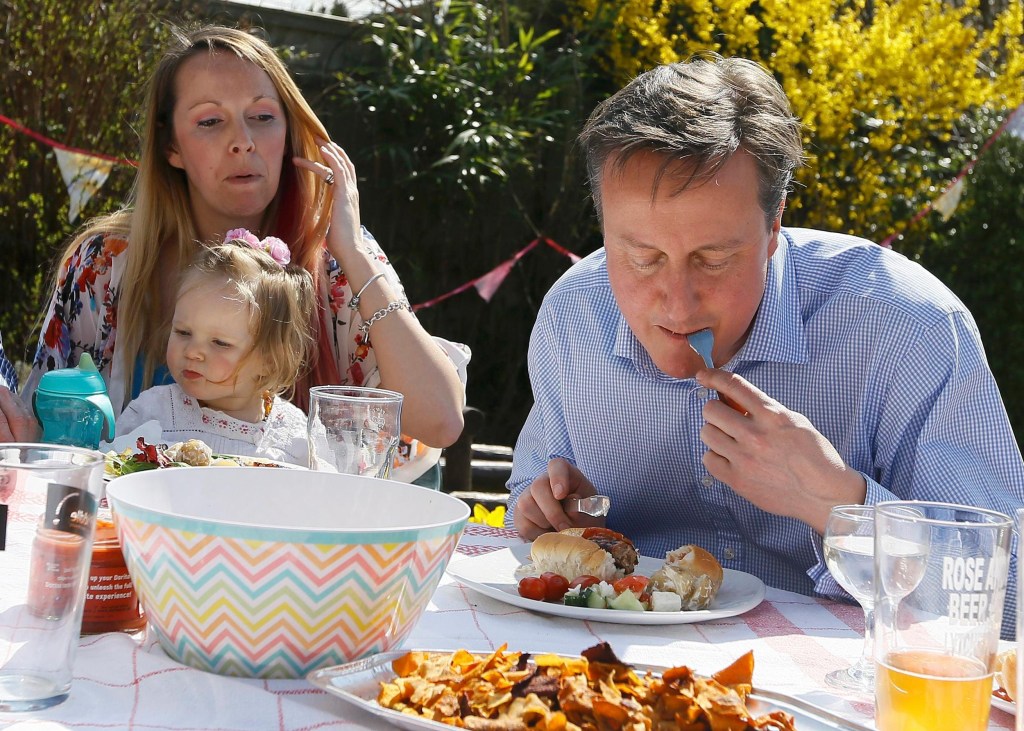 O primeiro-ministro britânico David Cameron come cachorro-quente, com o garfo