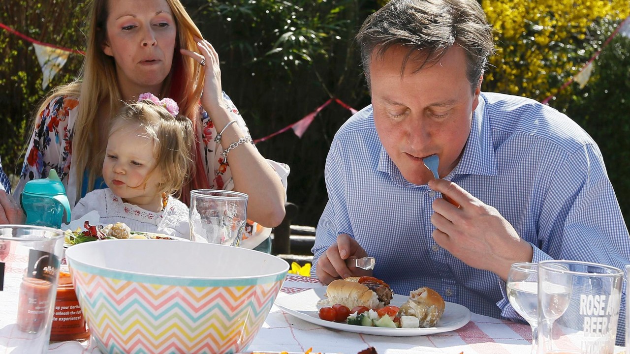 O primeiro-ministro britânico David Cameron come cachorro-quente, com o garfo