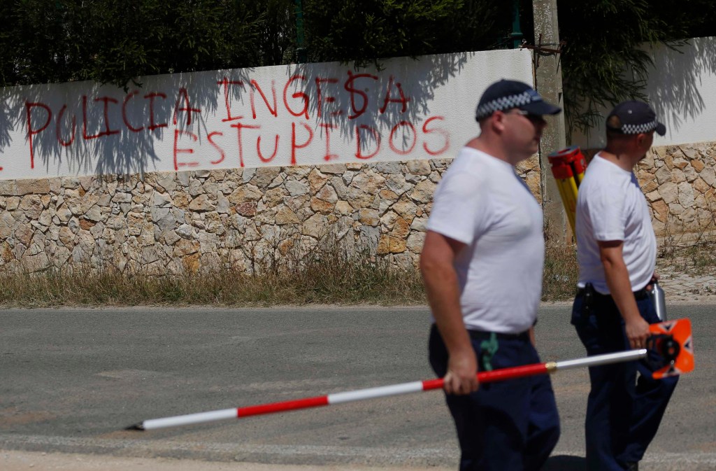 Policiais britânicos passam perto de pichação em muro na Praia da Luz, em Portugal