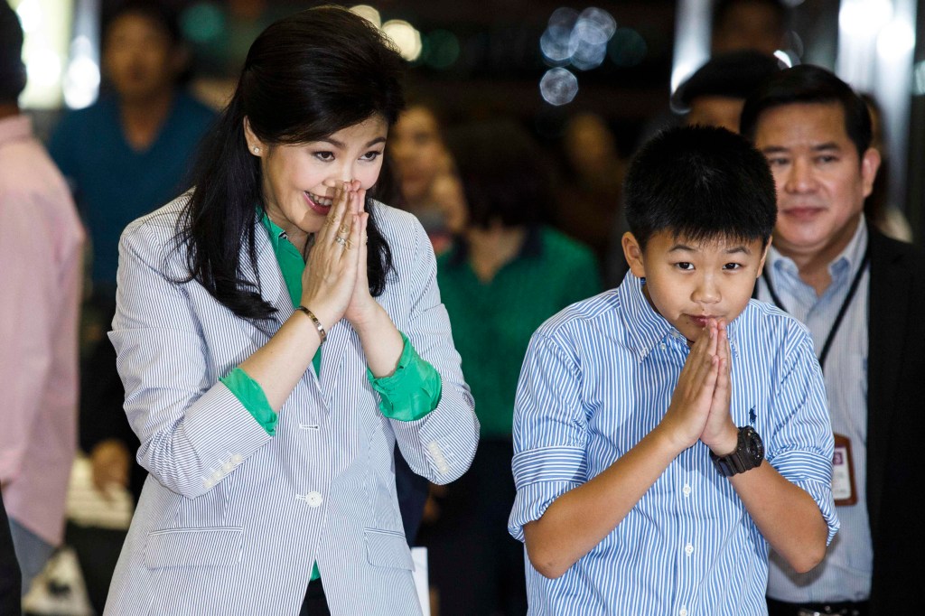A ex-primeira-ministra Yingluck Shinawatra e o filho Supasek Amornchat cumprimentam jornalistas ao chegar ao Aeroporto de Bangcoc, na Tailândia, no dia 23 de julho