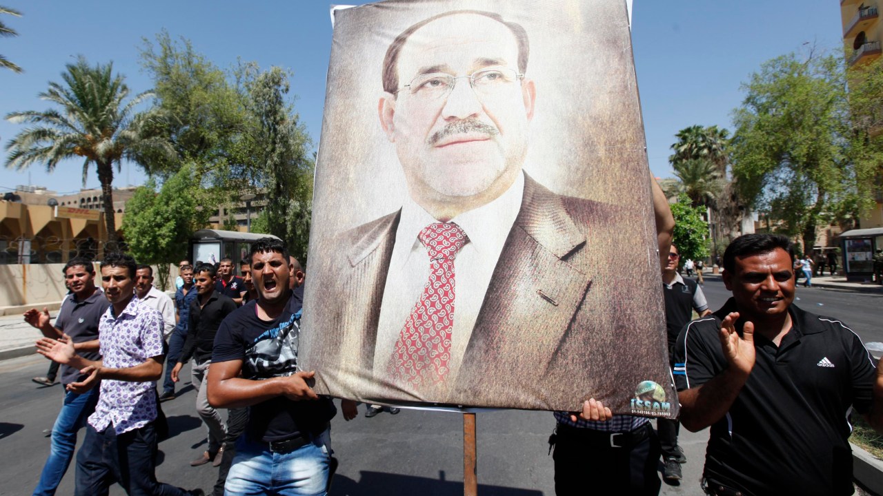 Iraquianos carregam desenho do primeiro-ministro Nouri al Maliki em marcha a favor do governo em Bagdá
