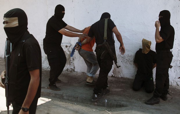 Membros de Hamas, vestidos de preto, se preparam para executar acusados de colaborar com Israel, em Gaza