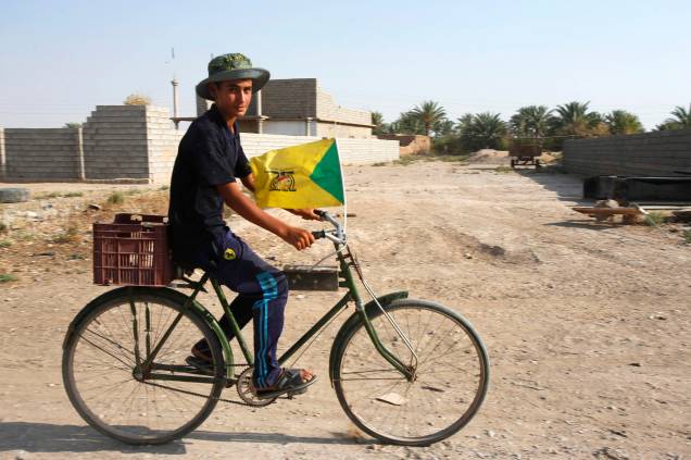 Garoto anda de bicicleta carregando uma bandeira Hezbollah em Amerli, Iraque - 01/09/2014