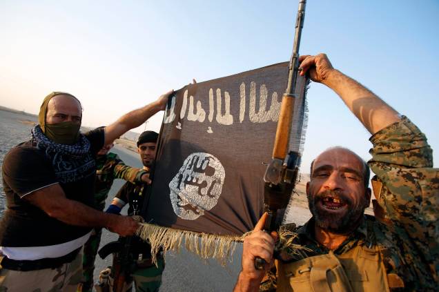 Milícia iraquiana posam com bandeira do Estado Islâmico para celebrar o rompimento do cerco da cidade de Amerli, Iraque - 01/09/2014