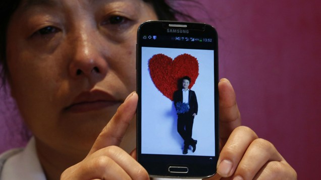 Feng Xuehong, cujo filho Wang Houbin estava a bordo do voo MH370 da Malaysia Airlines, guarda uma foto dele em seu celular
