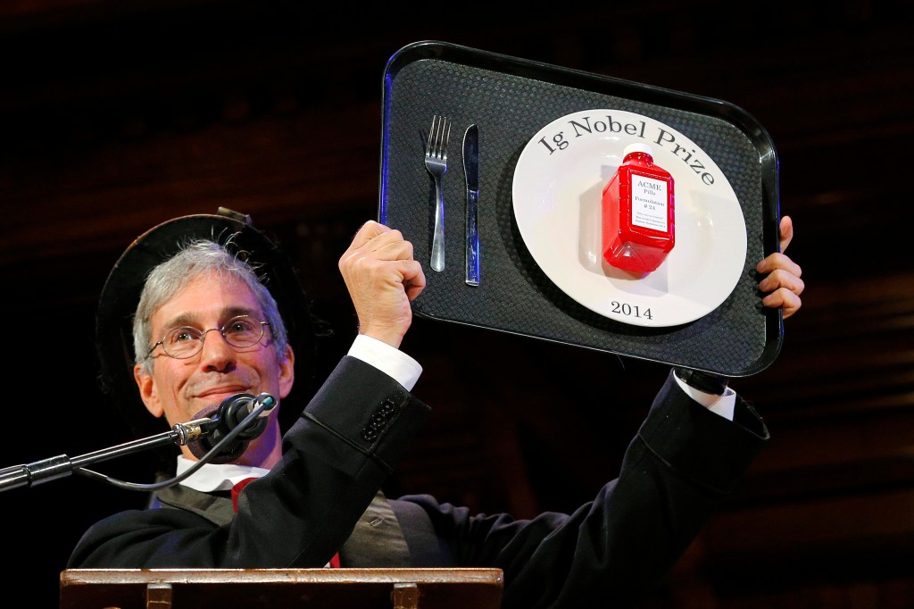 O mestre de cerimonias do Ig Nobel 2014, Marc Abrahams, mostra à plateia o troféu entregue aos premiados