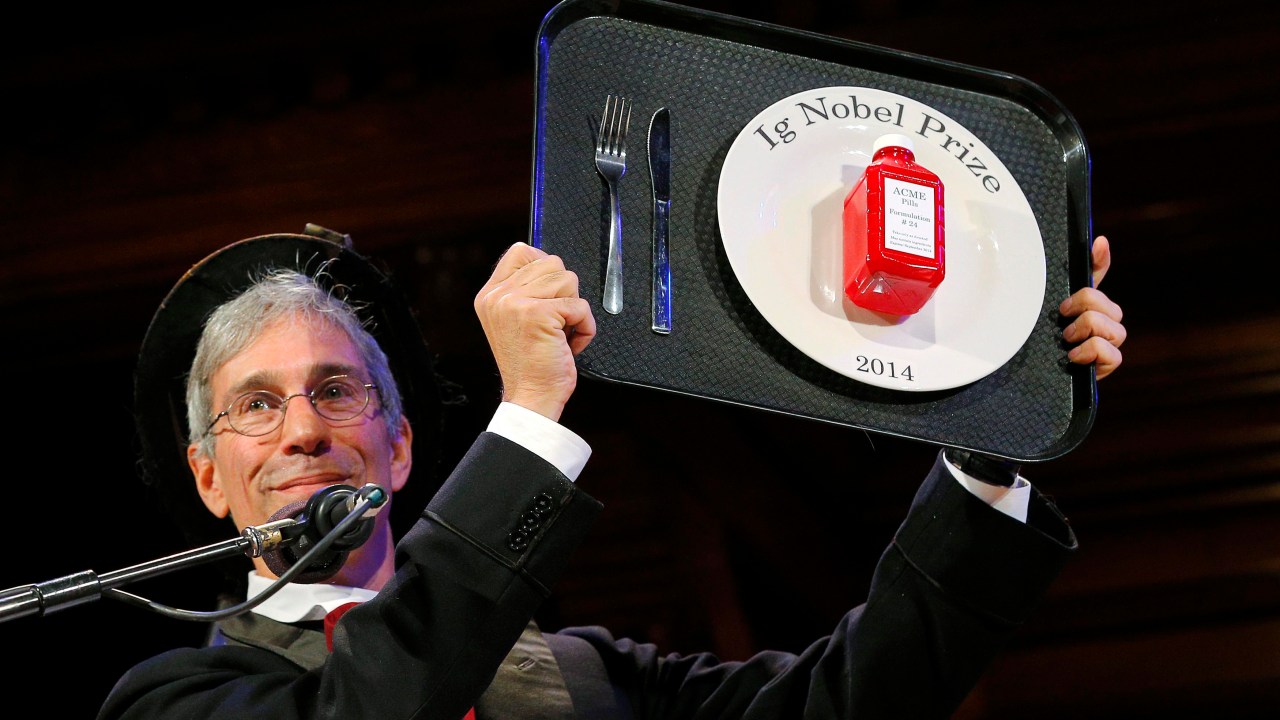 O mestre de cerimonias do Ig Nobel 2014, Marc Abrahams, mostra à plateia o troféu entregue aos premiados