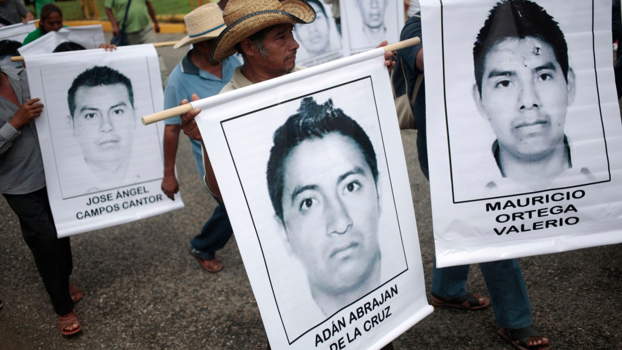 Pessoas carregam imagens de estudantes desaparecidos durante protesto em Acapulco, no México