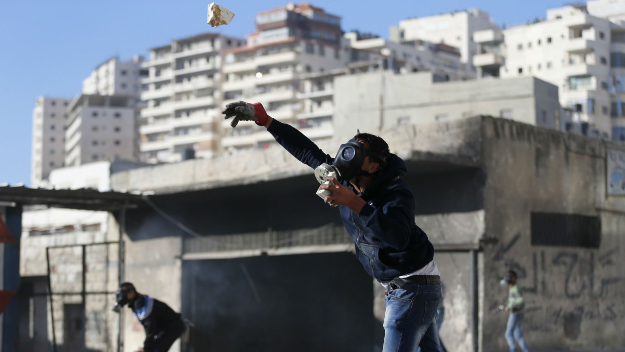 Palestino lança pedras contra as forças de segurança de Israel durante um protesto em Jerusalém