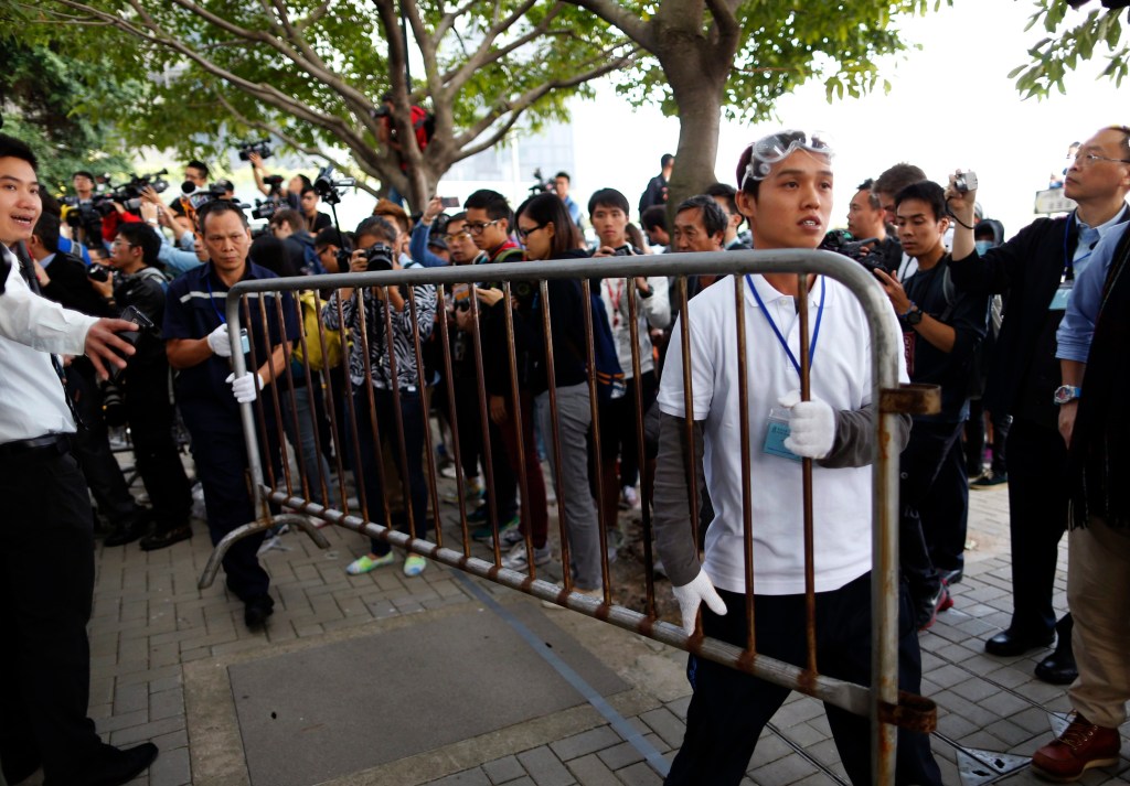 Manifestante pró-democracia (dir) e funcionário carregam grade retirada de área ocupada em Hong Kong por determinação judicial