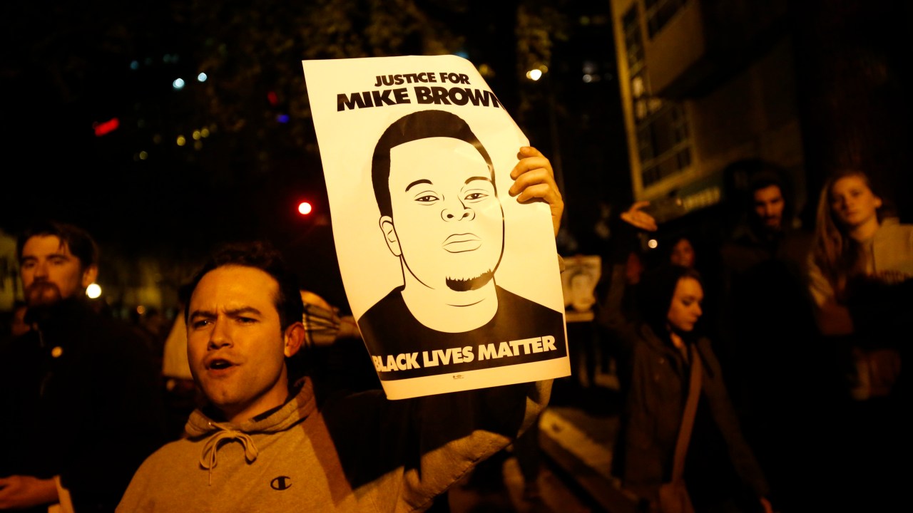 Manifestante levanta cartaz pedindo justiça para Michael Brown, jovem morto por policial no Missouri
