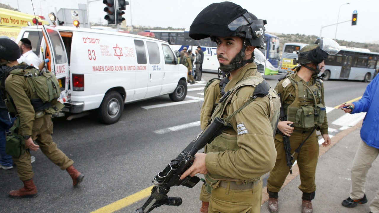 Soldado israelense monta guarda no local em que uma família israelense foi atacada com ácido por um palestino