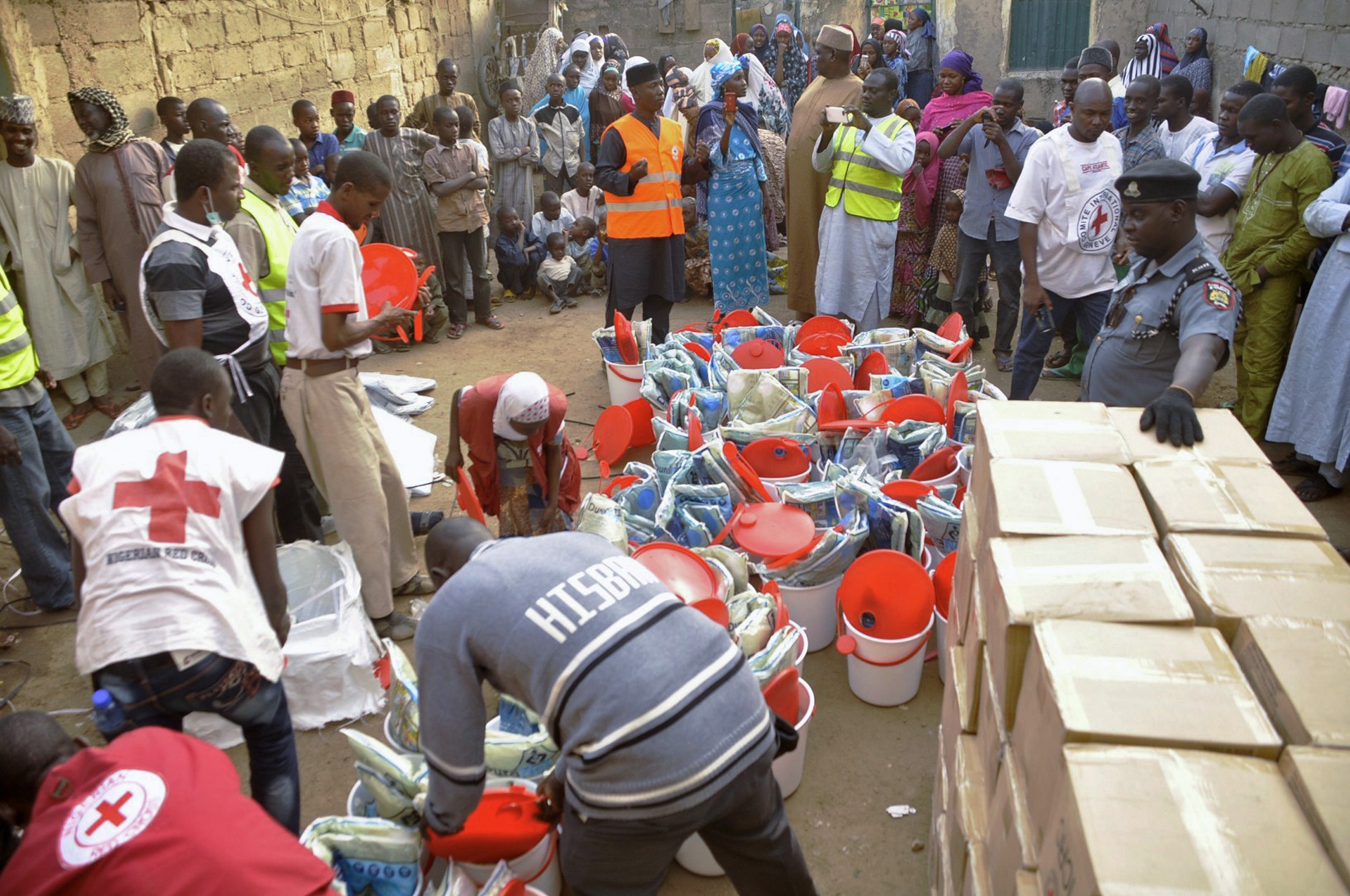 Pessoas que fugiram da violência do Boko Haram recebem material de ajuda da Cruz Vermelha em Kano, na Nigéria