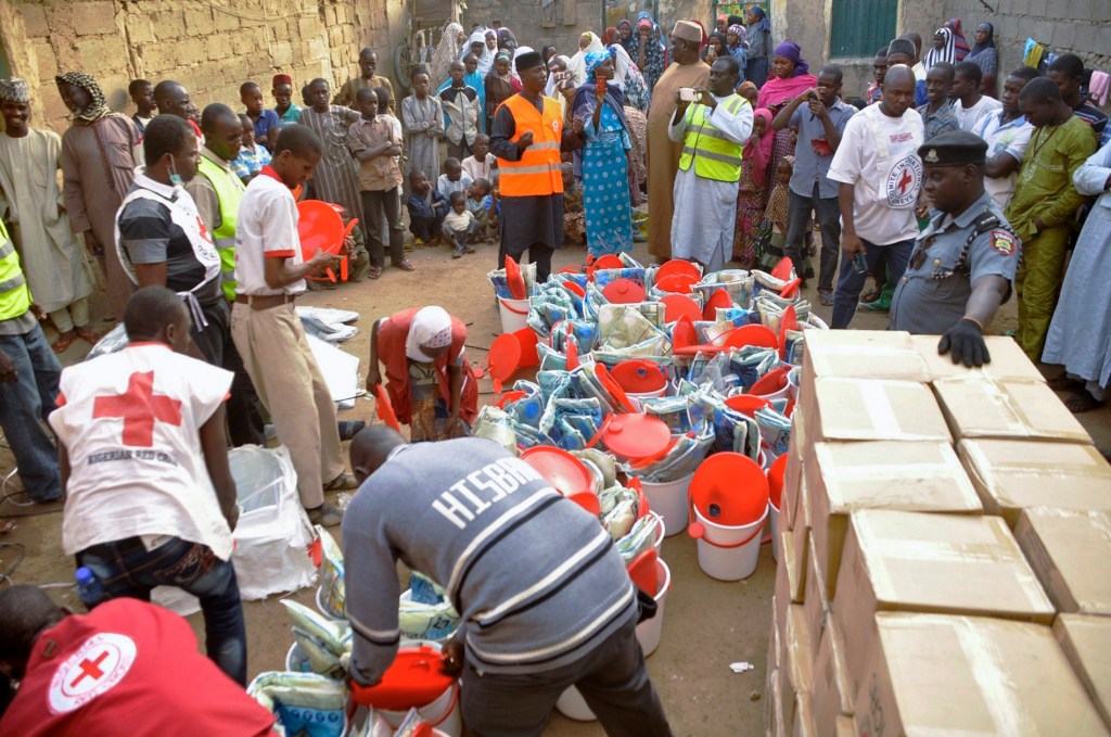 Pessoas que fugiram da violência do Boko Haram recebem material de ajuda da Cruz Vermelha em Kano, na Nigéria