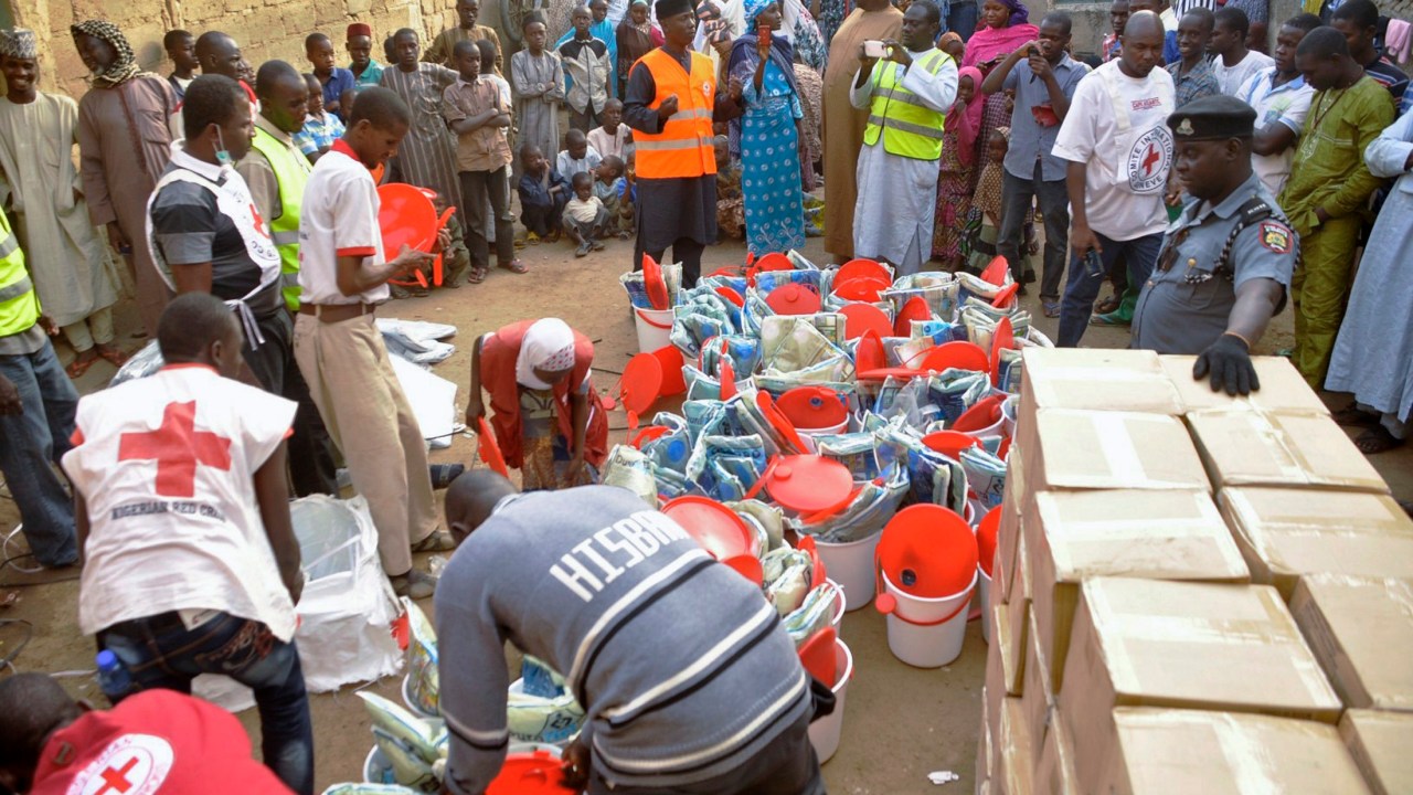 Pessoas que fugiram da violência do Boko Haram recebem material de ajuda da Cruz Vermelha em Kano, na Nigéria