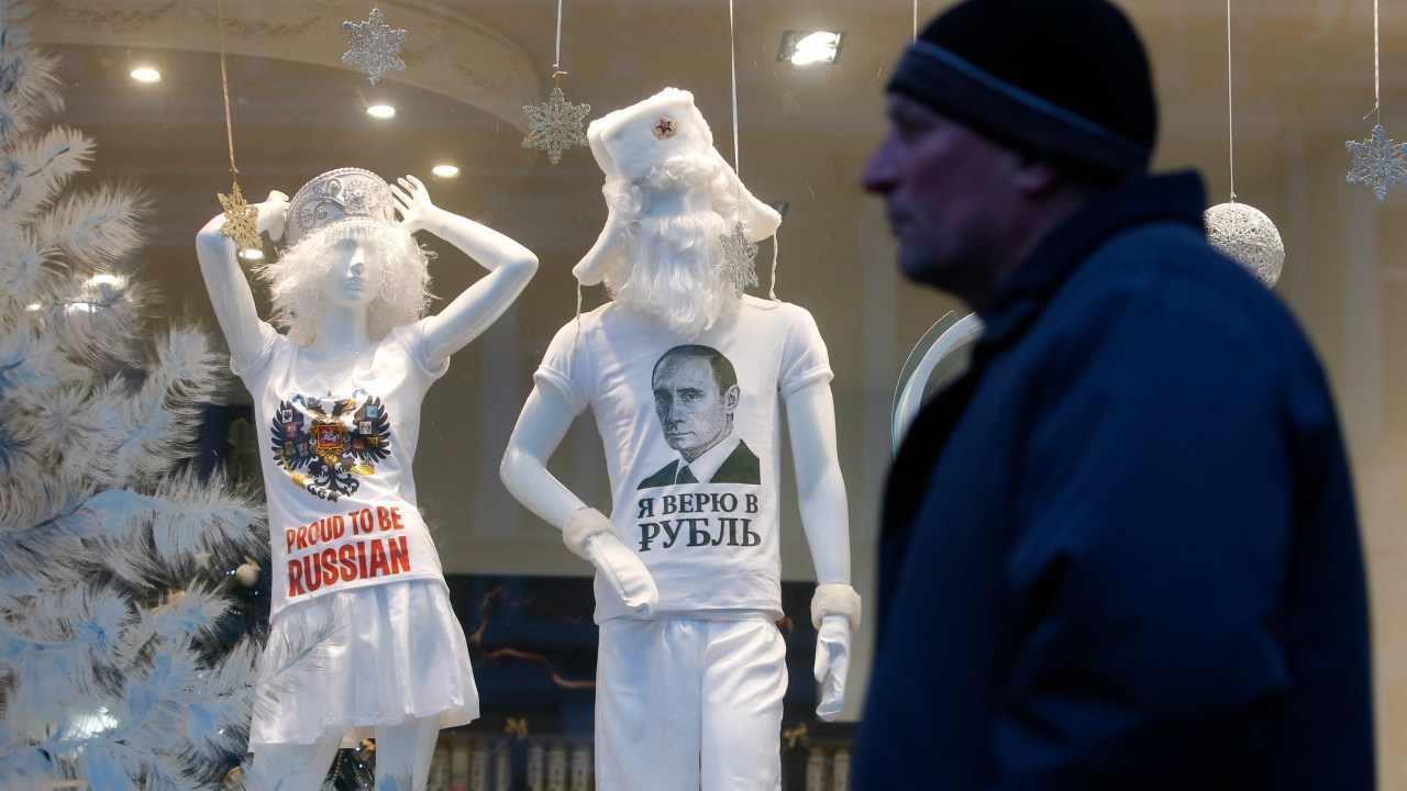 Homem passa em frente a vitrine em Moscou que mostra camisetas com o retrato de Vladimir Putin e com a frase “Orgulho de ser Russo”