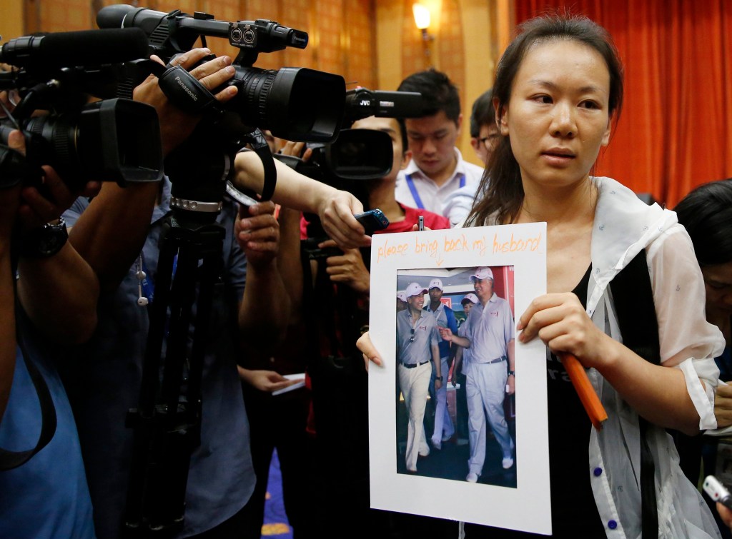 Mulher de um passageiro do voo MH370 da Malaysia Airlines mostra foto do marido para jornalistas