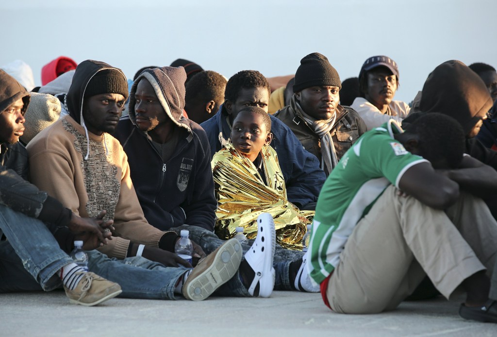 Imigrantes descansam após desembarcarem no porto siciliano de Augusta