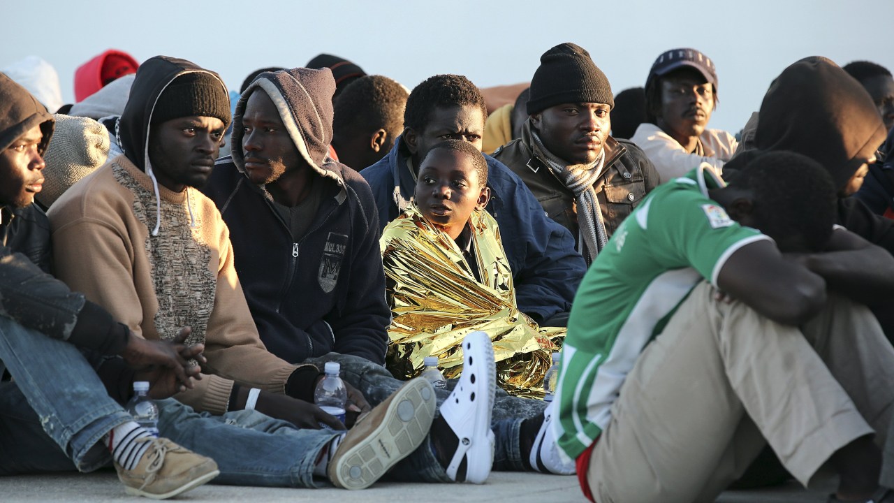 Imigrantes descansam após desembarcarem no porto siciliano de Augusta