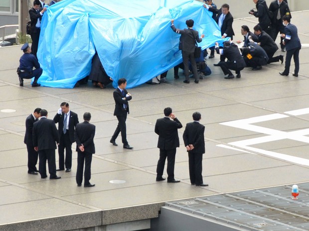 Policiais e agentes isolam o drone que caiu sobre a residência oficial do premiê japonês