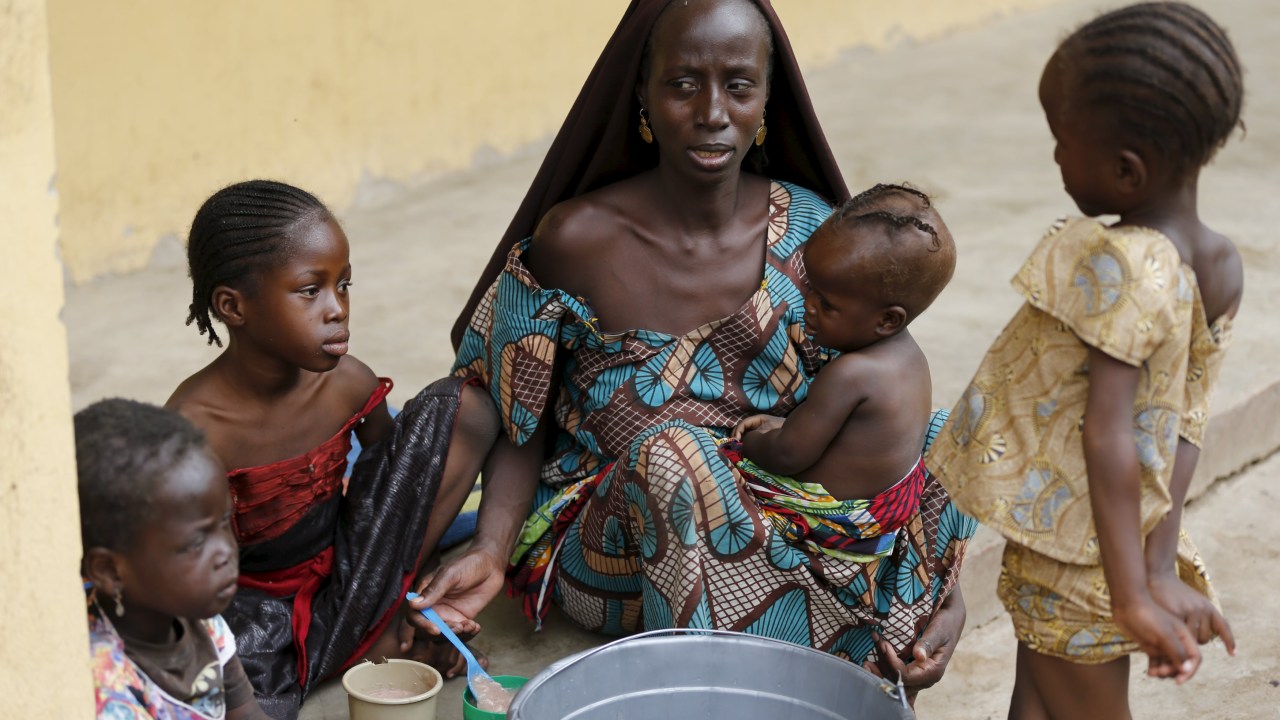 Mulher resgatada por soldados nigerianos depois de ser mantida refém pelo Boko Horam alimenta crianças em Yola, para onde vítimas foram levadas