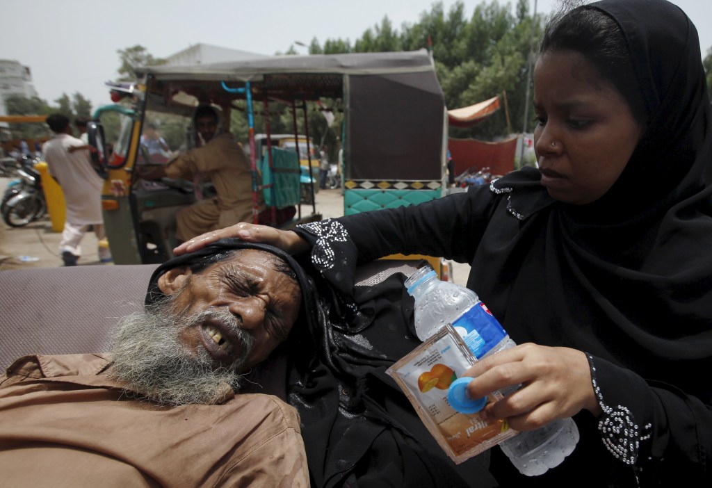 Mulher auxilia um idoso desidratado no Paquistão