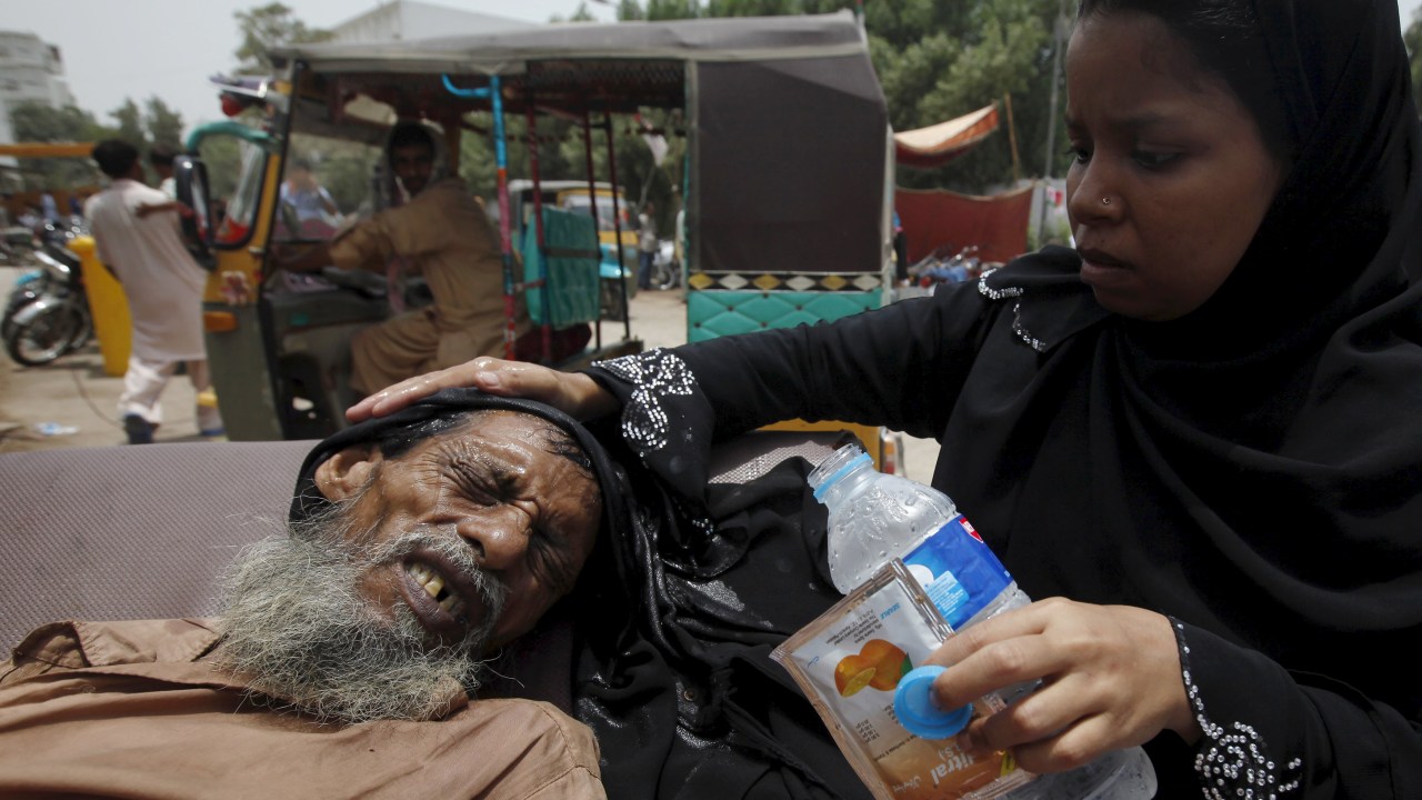 Mulher auxilia um idoso desidratado no Paquistão