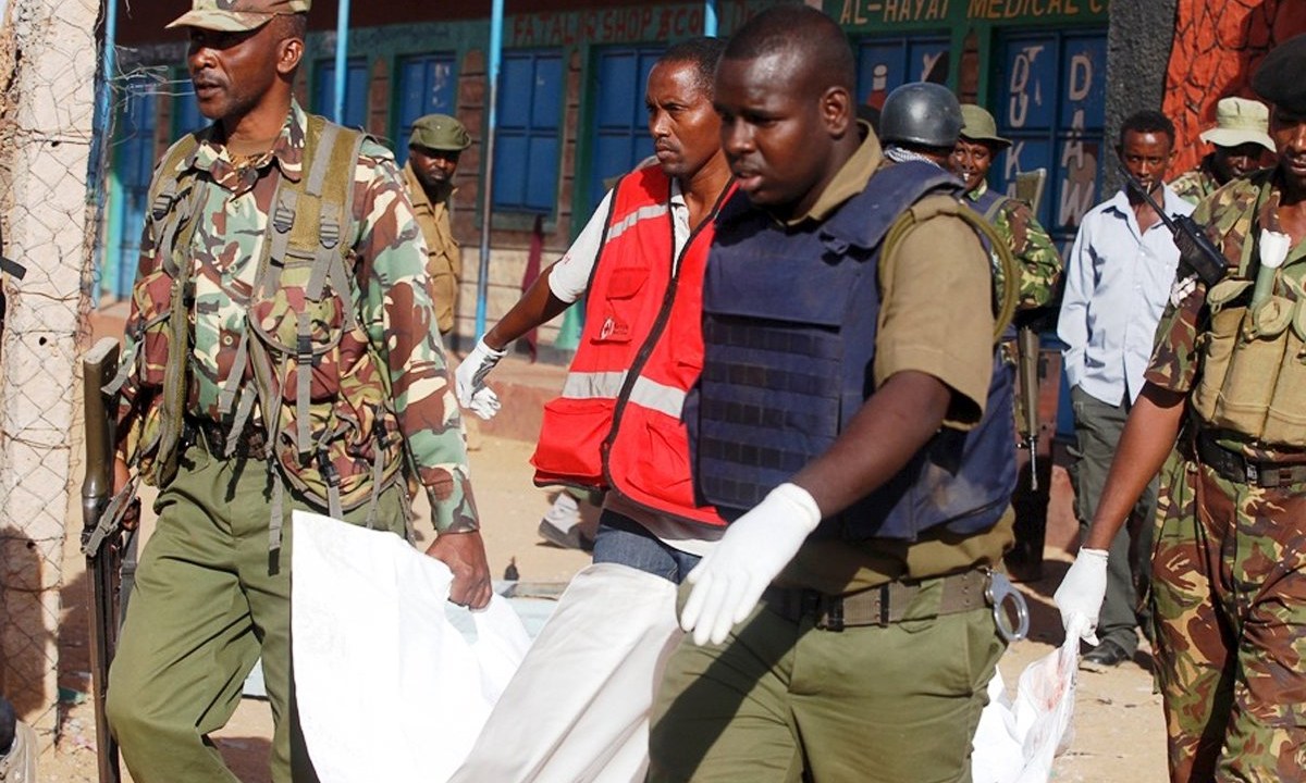 Oficiais da polícia queniana e membros da Cruz Vermelha carregam corpo de uma das vítimas de ataque do grupo terrorista Al Shabab na cidade de Mandera, próxima à fronteira com a Somália