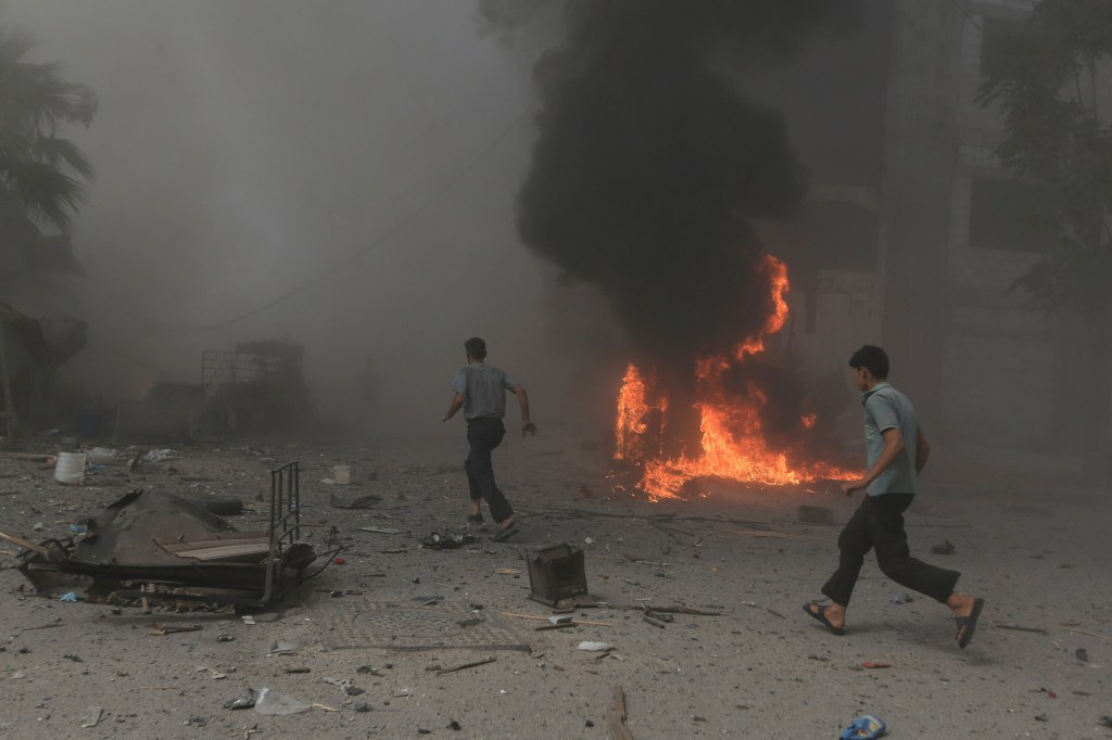 Homens correm em marcado atingido por bombardeio de aliados do governo de Bashar al-Assad, em Damasco, Síria